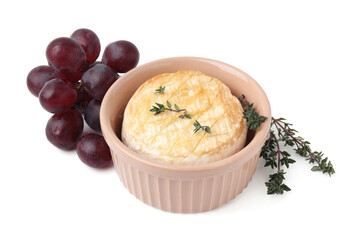 Tasty baked camembert in bowl, grapes and thyme on white background