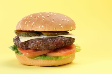 Burger with delicious patty on yellow background, closeup