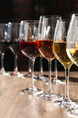 Different tasty wines in glasses on wooden table