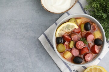 Meat solyanka soup with thin dry smoked sausages served on grey table, flat lay. Space for text