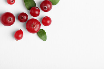 Fresh ripe cranberries and green leaves on white background, flat lay. Space for text