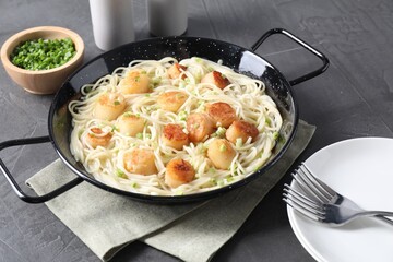 Delicious scallop pasta with green onion served on grey table