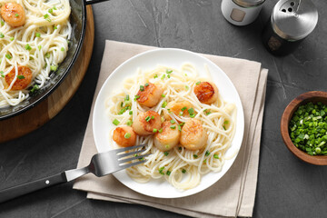 Delicious scallop pasta with green onion served on grey table, flat lay