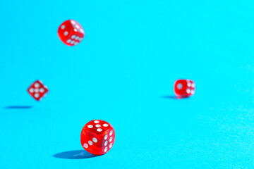 Many red game dices falling on light blue background