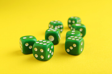 Many green game dices on yellow background, closeup