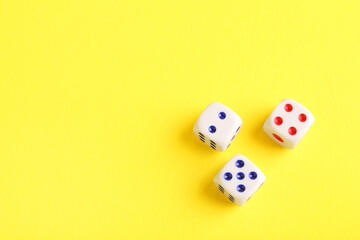 Three white game dices on yellow background, flat lay. Space for text