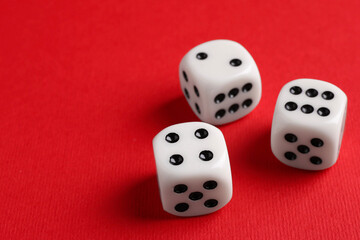 Three white game dices on red background, closeup