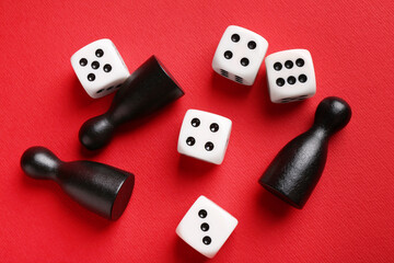 Many white dices and black game pieces on red background, flat lay
