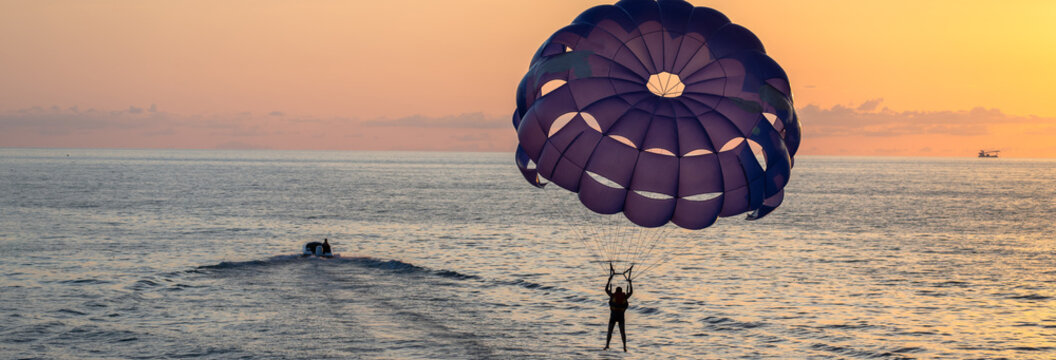 scene of a man parachuting with a purple parachute above the sea