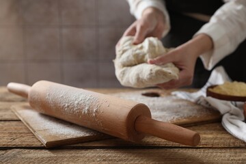Woman making dough at wooden table, selective focus