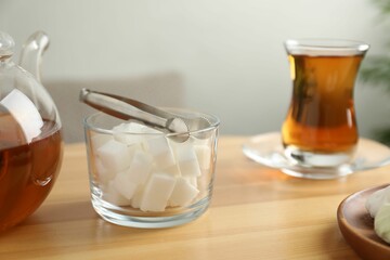 Sugar cubes and aromatic tea in glass on wooden table