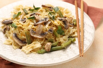 Vegetarian pasta with mushrooms, parsley, string beans and cheese on orange textured table, closeup