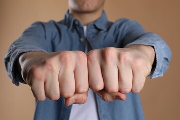 Man showing fists with space for tattoo on beige background, selective focus