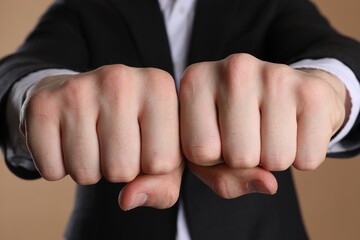 Obraz premium Businessman showing fists with space for tattoo on beige background, selective focus