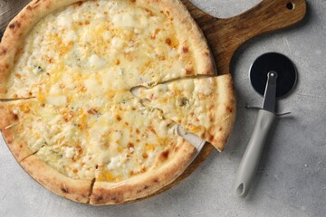 Delicious cheese pizza and cutter on light grey table, flat lay