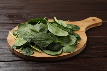 Bowl with fresh spinach leaves on wooden table, closeup