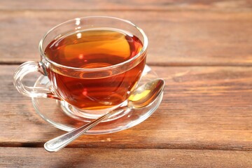 Glass cup of tea and spoon on wooden table