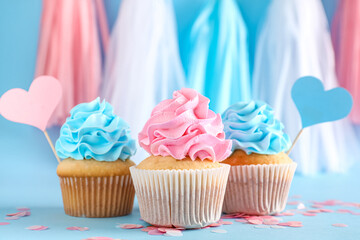 Delicious cupcakes with decorations on blue background. Gender reveal party concept