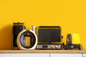 Different household appliances on kitchen counter near yellow wall, closeup