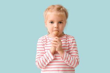 Cute little girl with sweet lollipop on blue background