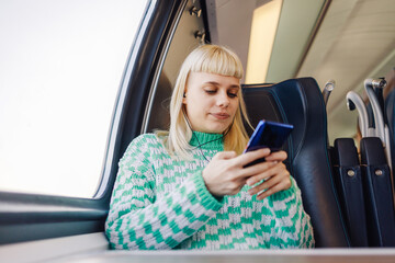 A traveler sitting in train and using her cellphone during journey.