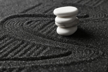 White spa stones on black sand with lines, closeup. Zen concept