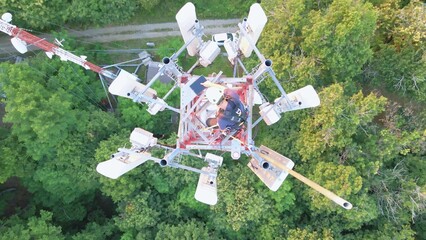 Engineer technician maintenance checking on top roof of Telecommunication tower with 5G cellular network. Aerial top down base station smart city global connection