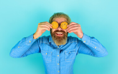 Smiling bearded man covered eyes with oatmeal cookies. Tasty sweet snack. Handsome male with...