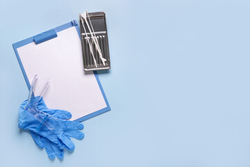 Clipboard with medical gloves, gynecological speculum and pap smear test tools on blue background