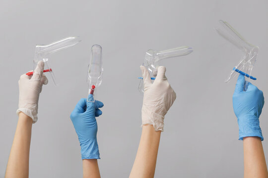 Hands in medical gloves with gynecological speculums on white background
