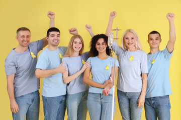 Young woman undergoing chemical therapy course and people with yellow awareness ribbons on color background. World Cancer Day