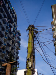 Many wires are piled on a wooden pole in a modern city. Electrification of an Asian city.
