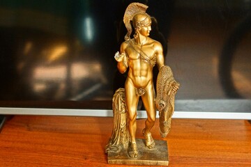 one plastic antique yellow small figurine of a naked Greek strong warrior in a helmet stands on a...
