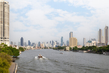 Urban cityscape with skyscrapers and boats on the Chao Phraya River in Bangkok, Thailand at day. Copy space.