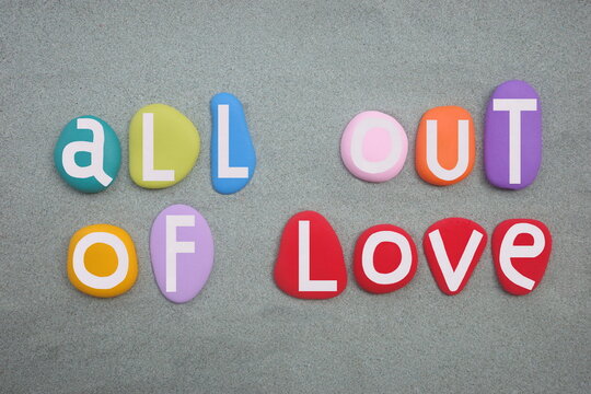 All out of love, creative slogan composed with hand painted multi colored stone letters over green sand