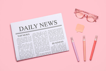 Newspaper with eyeglasses, sticker and markers on pink background