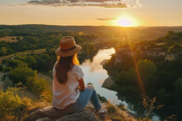 Fototapeta premium Woman sitting on rock overlooking river, suitable for nature themes