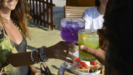 brindisi tra amici con cocktail colorati in un bar all'aperto in riva al mare