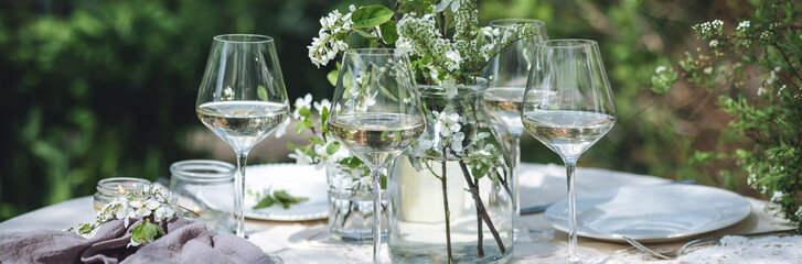 Rustic zero waste wedding decor with natural elements. Fresh spring blooming flowers, candles, linen napkins, wine glasses. Eco friendly decoration for special holiday dinner. Romantic place banner