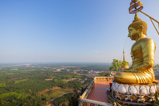Scenic view of the surrounding area and a big golden Buddha statue on top of the mountain at the Tiger Cave Temple (Wat Tham Suea (Sua)) in Krabi, Thailand, on a sunny day.