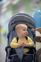 a one-year-old child, a boy, eats on the road, has a snack on the way in a stroller