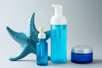 Set of cosmetic products and decorative starfish on light grey background