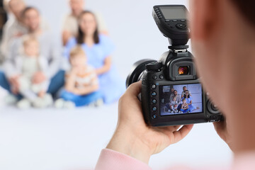 Male photographer taking picture of big family in studio, closeup