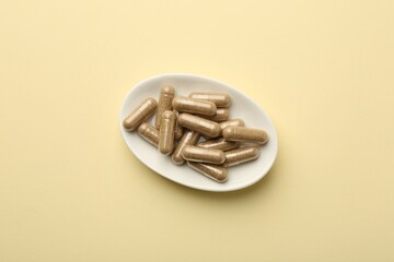 Vitamin capsules on pale yellow background, top view