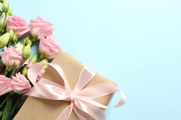 Happy Mother's Day. Beautiful flowers and gift box on light blue background, flat lay. Space for text