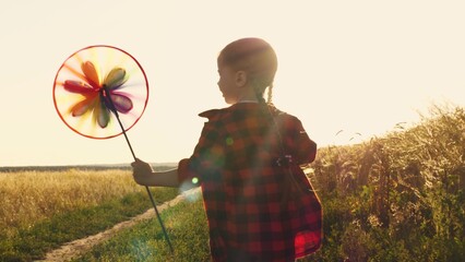 the pinwheel begins to play, child kid runs through park windmill hands, smile face, hand spinning...