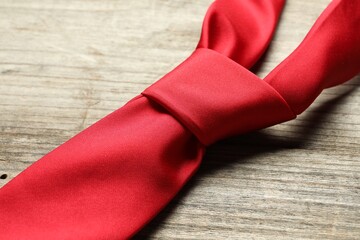 One red necktie on light wooden table, closeup