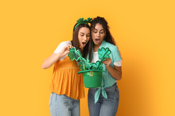 Beautiful young women with leprechaun hat and decorative glasses on yellow background. St....