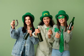 Beautiful young women with bottles of beer, clover and horseshoe on green background. St. Patrick's...