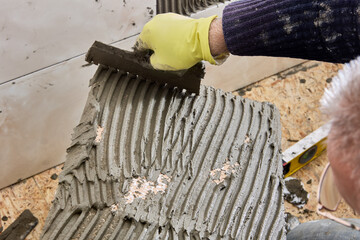 Notched trowel is used to apply cement mortar to surface of tile.